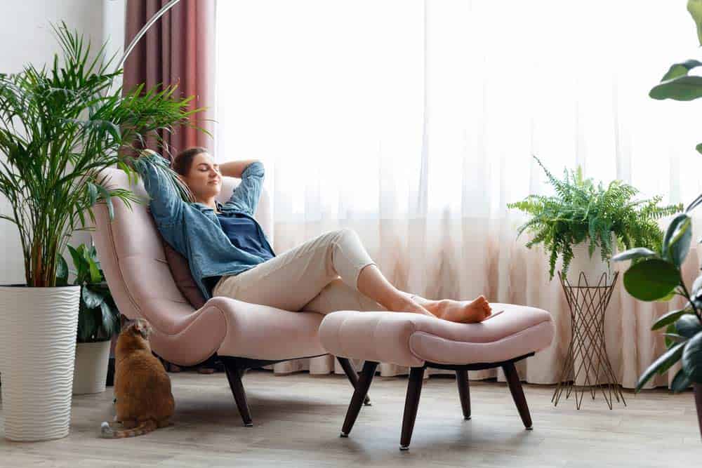 Relaxsessel mit Hocker und Pflanzen im Zimmer sorgen für ein entspanntes und gutes Wohnklima (depositphotos.com)
